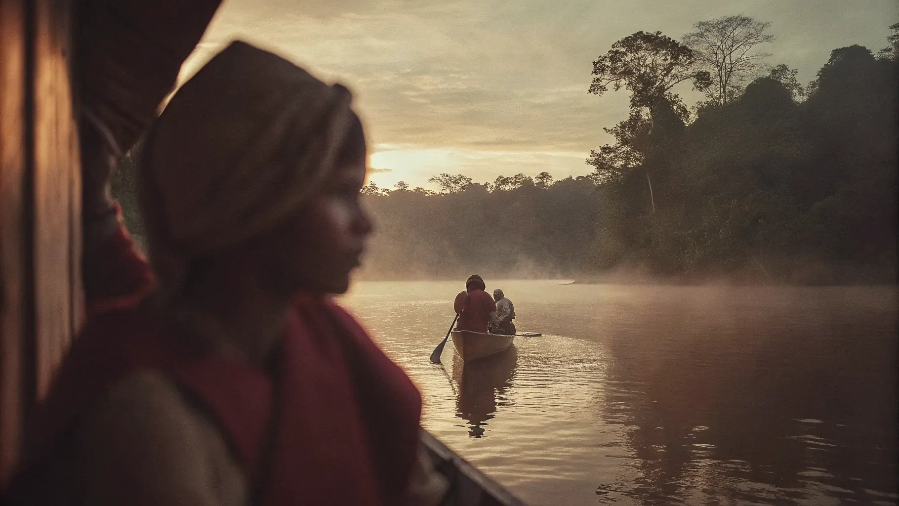 Dawn mist rising over the Amazon river with a small canoe in the distance